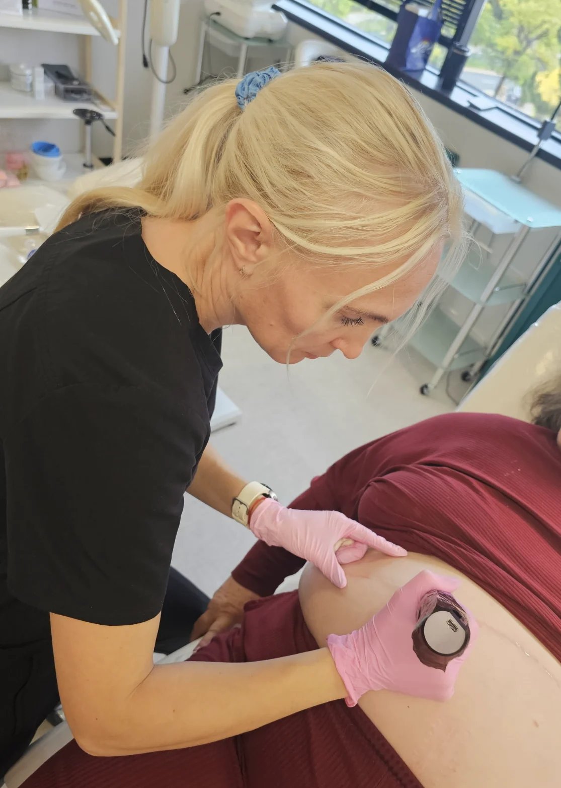 Healthcare professional in pink gloves performing a precise procedure in a clinical setting